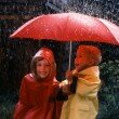 Small boy and girl under umbrella in rain